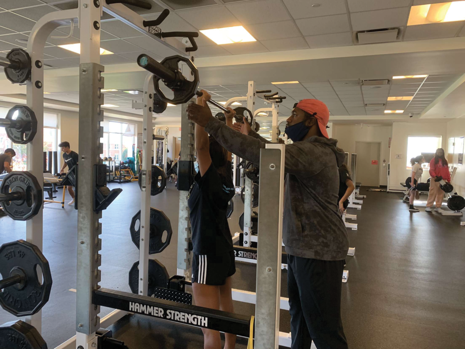 Trainer Malcom Tobias helping a LFA athlete lift. 