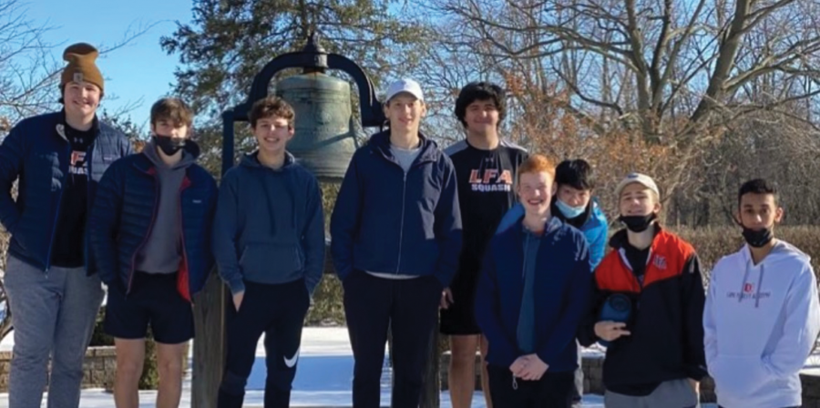 The squash team stands in front of LFA's famous bell. 