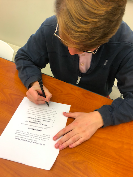 Finn Harrison ‘23 reenacts Joe Biden signing the Inflation Reduction Act. 