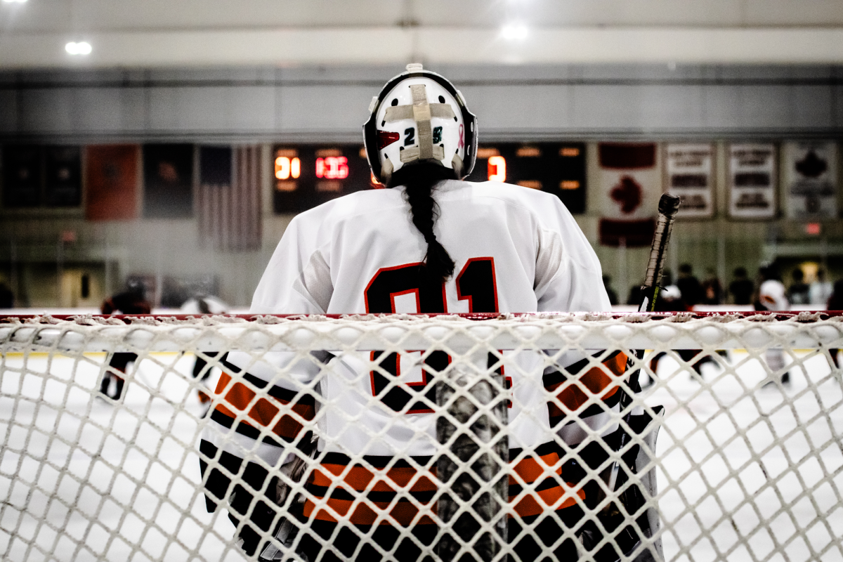 The girls hockey goalie defends the net.