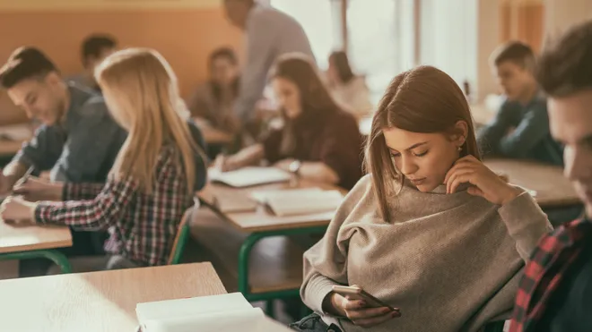 A student focuses on their phone in class.