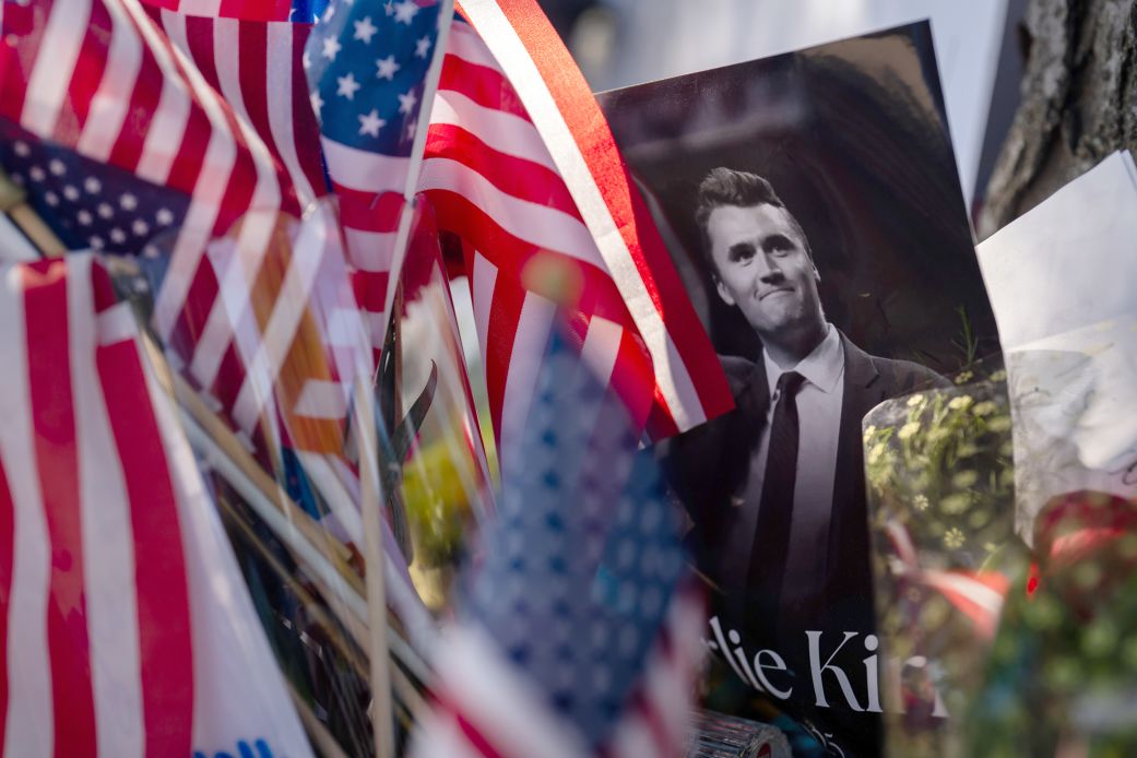 American flags fly next to a memorial photo of Charlie Kirk.