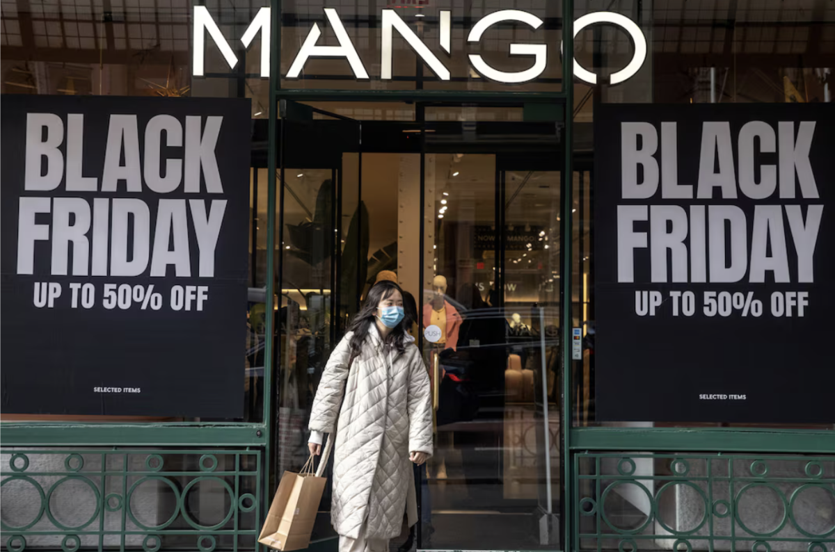 A shopper exits a MANGO store on Black Friday with a recent purchase.