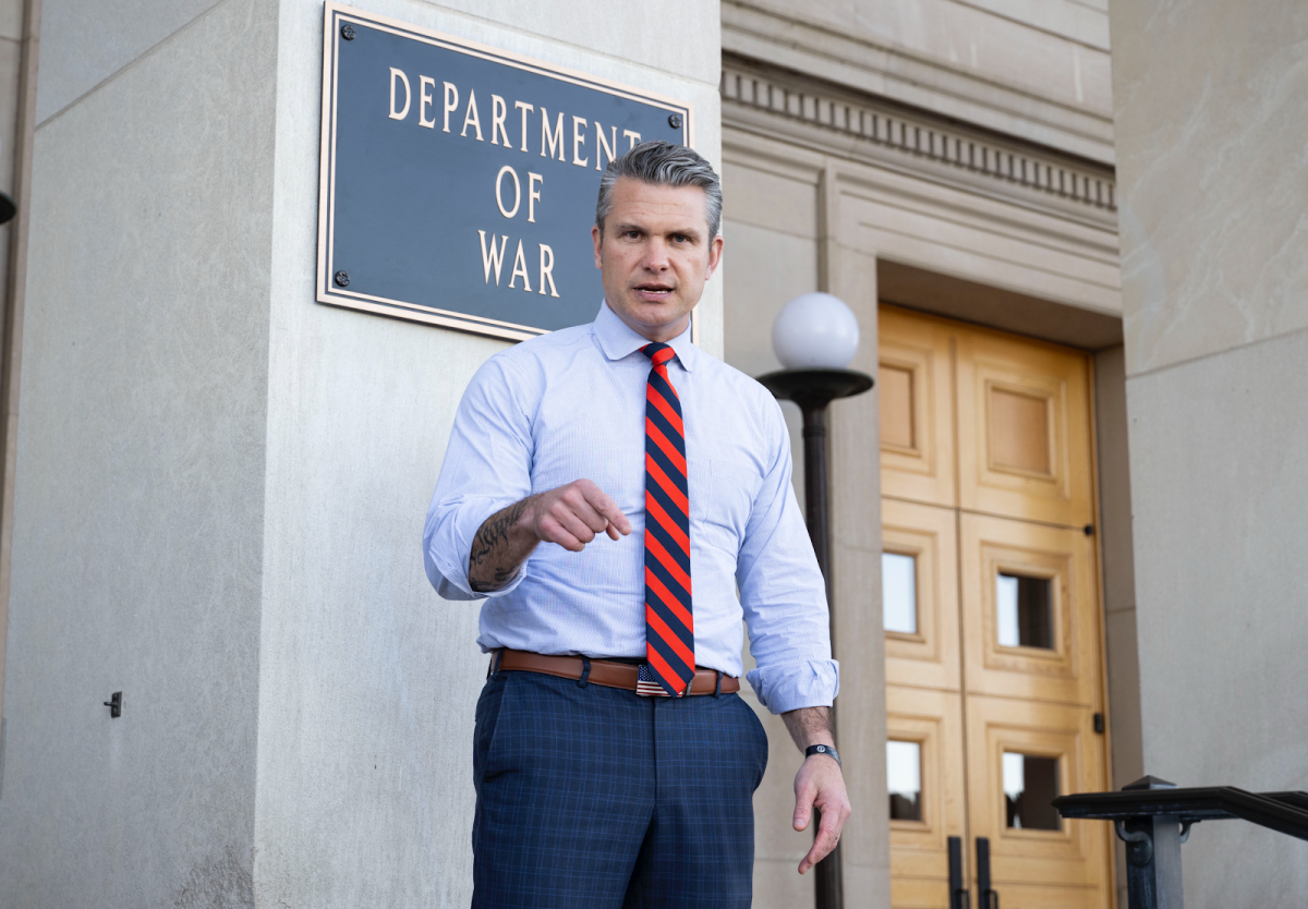 Secretary of Defense Pete Hegseth stands next to his new “Department of War” sign.