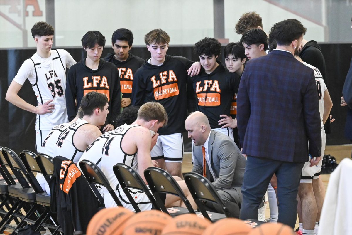 The Boys Varsity Basketball team gathers around Head Coach Kyle Koncz during a timeout.