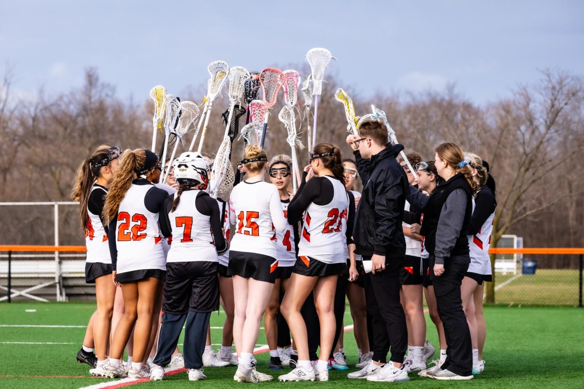 Girls Varsity Lacrosse players huddle before a game.
